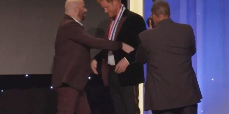 Príncipe Harry recibe medalla de las manos de Jhonn Travolta