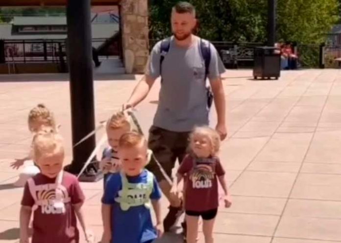 Hombre saca a pasear a sus hijos con correa