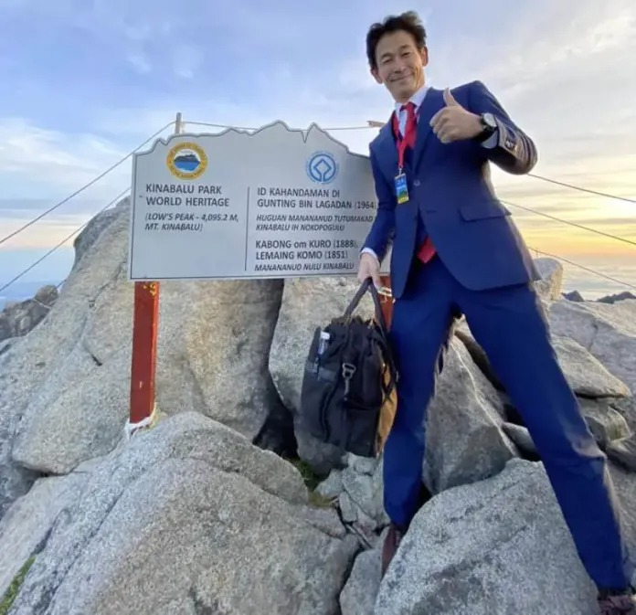 Un sastre escala alta montaña con traje y zapato de cuero