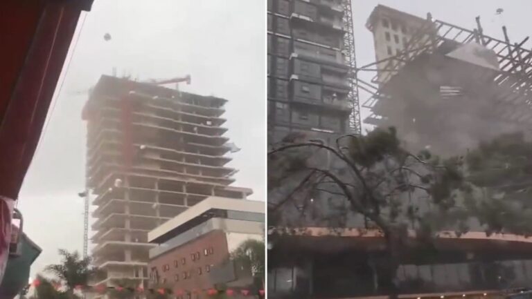 Dos trabajadores se agarran de un andamio para no caer de un edificio